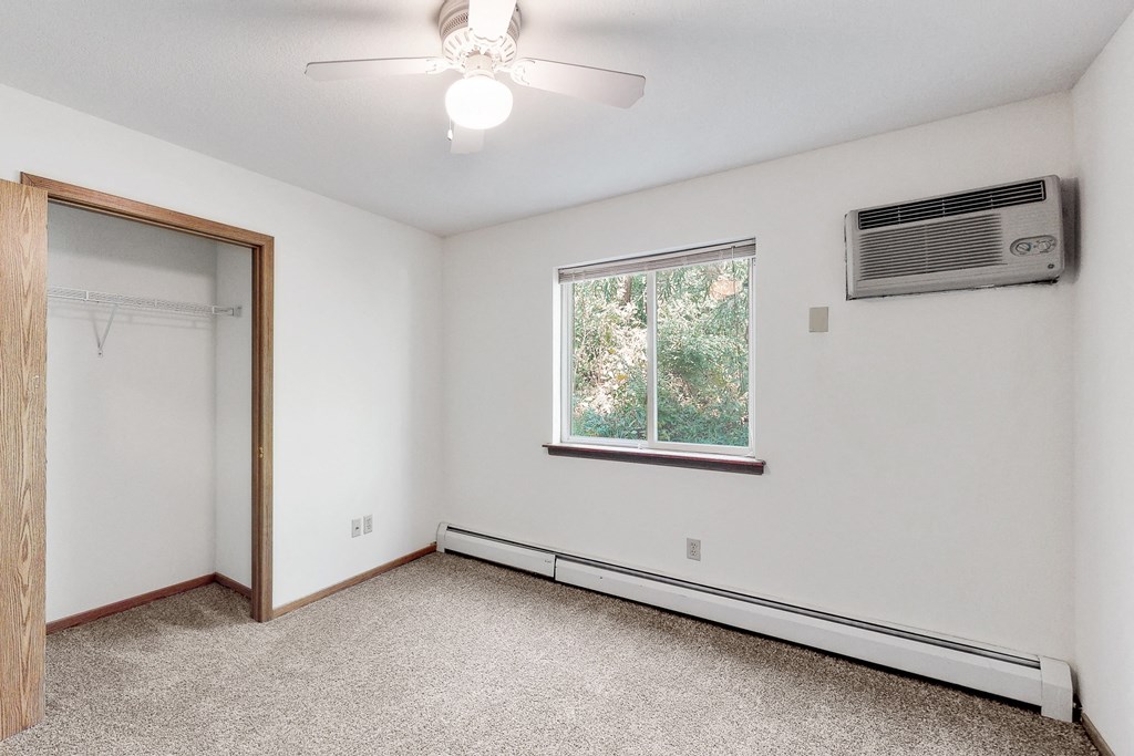 an empty room with white walls and a window and a ceiling fan