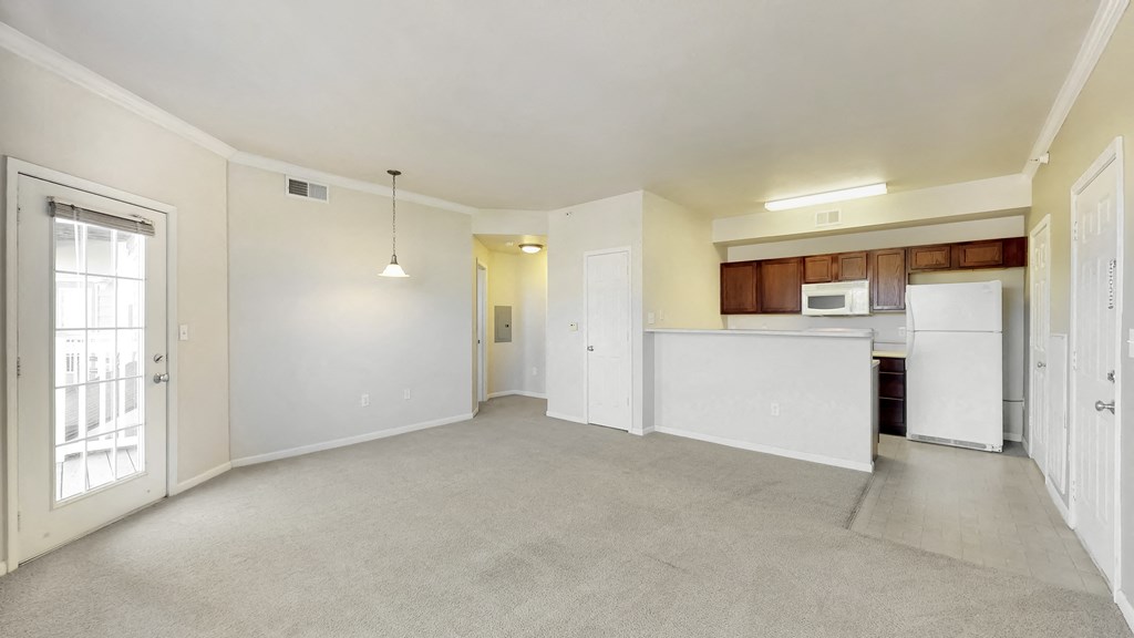 the living room and kitchen of an apartment with white walls and white appliances