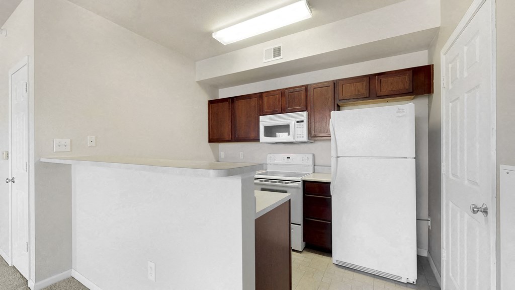 an empty kitchen with white appliances and wooden cabinets