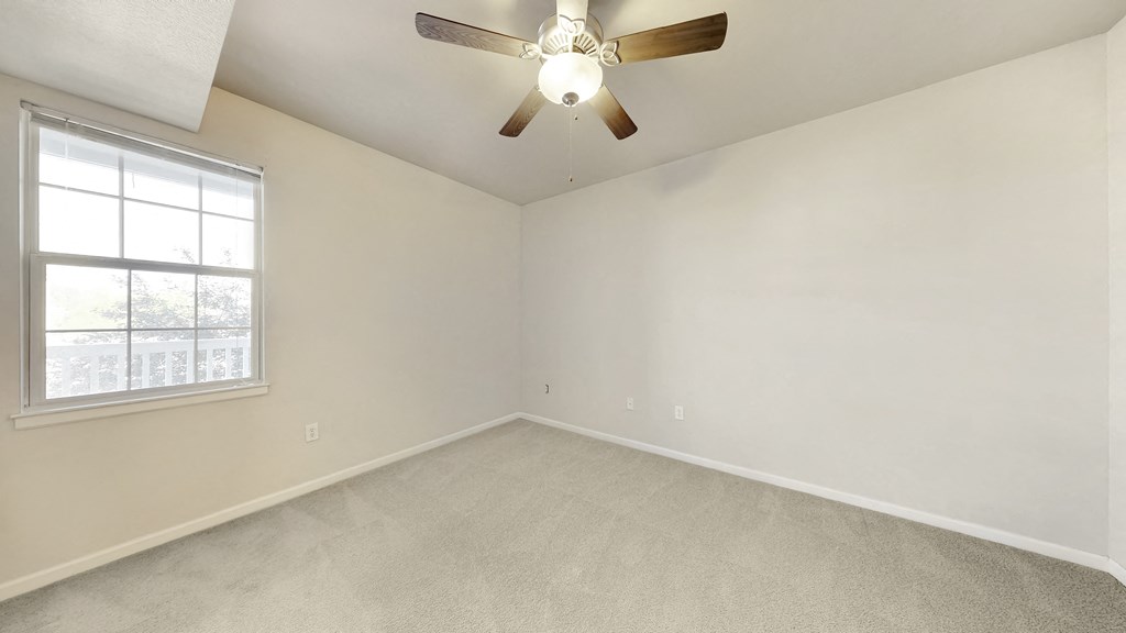 an empty living room with a ceiling fan and a window