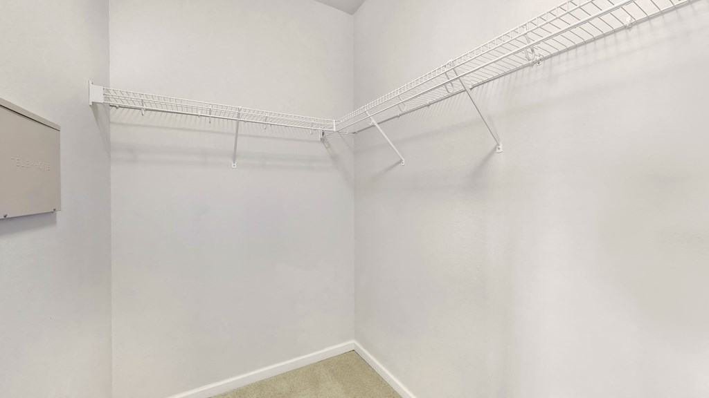 an empty closet with white walls and a wire rack on the wall
