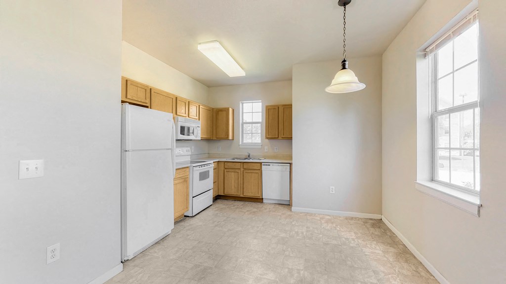 an empty kitchen with white appliances and wooden cabinets