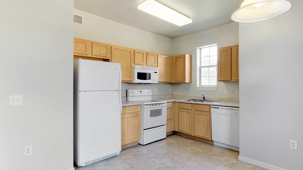 an empty kitchen with white appliances and wooden cabinets