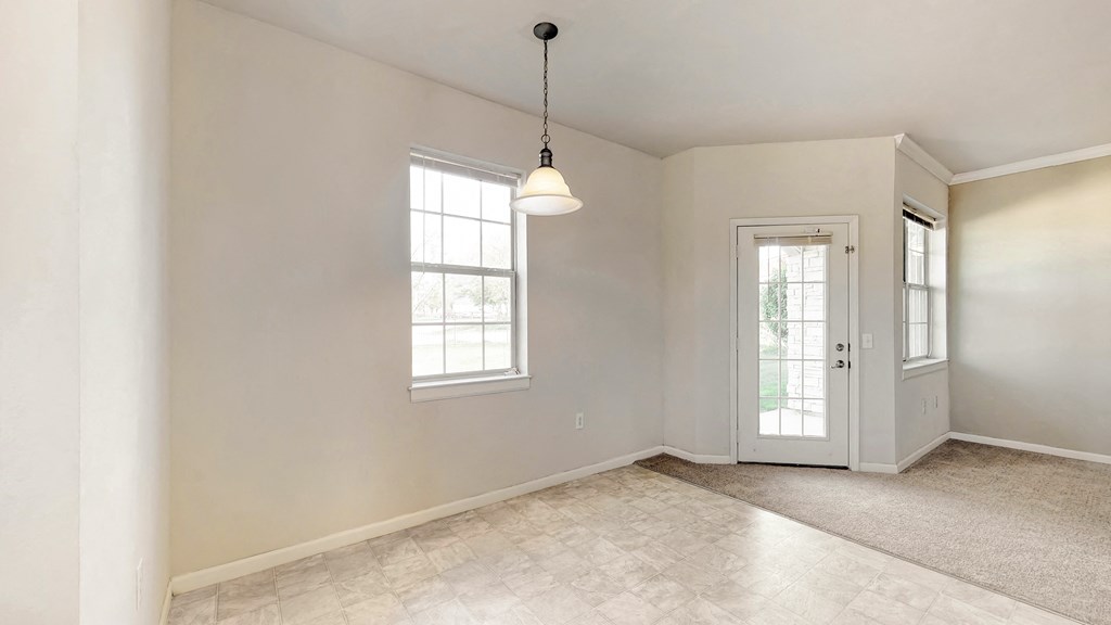 an empty living room with a white door and a window