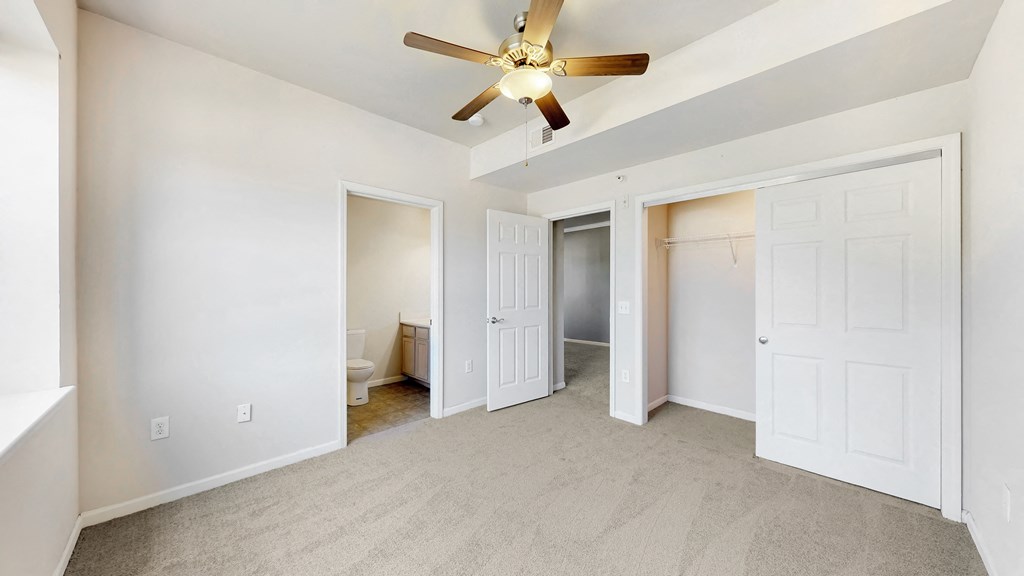 an empty living room with a ceiling fan and a closet