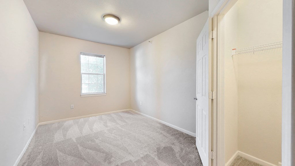 an empty room with a door to a closet and a window