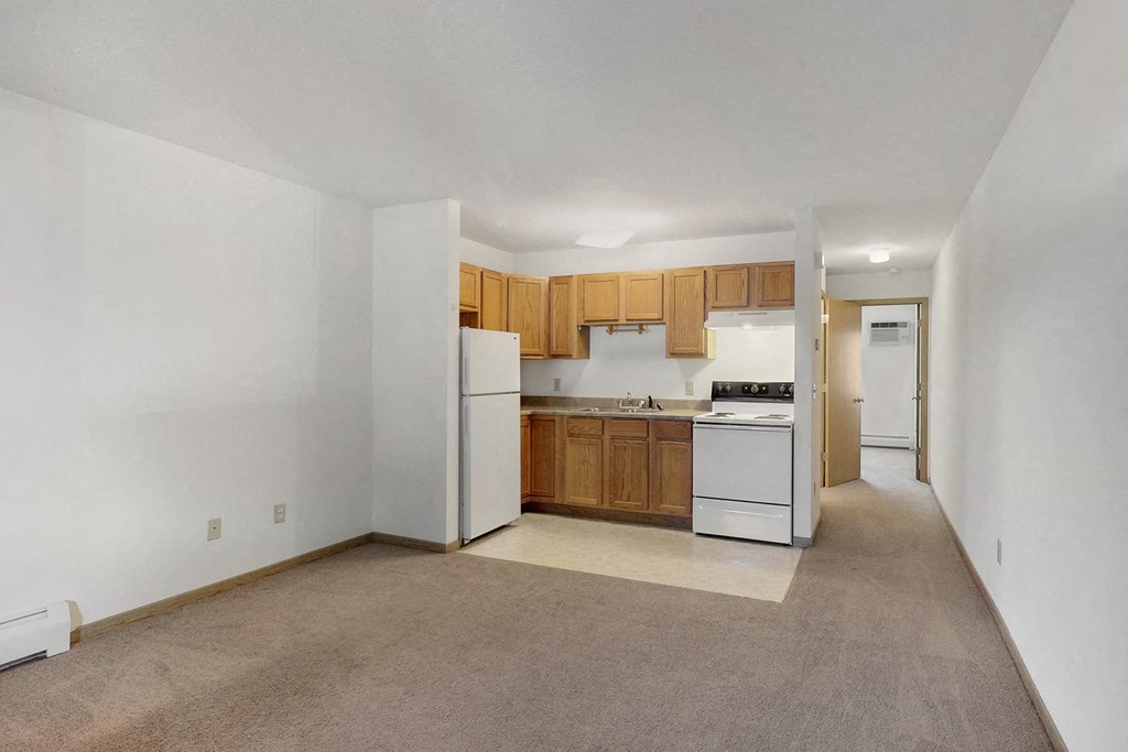 an empty kitchen with white appliances and wooden cabinets