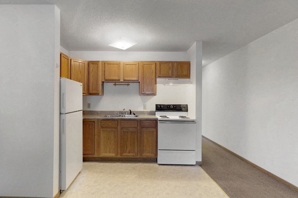 an empty kitchen with white appliances and wooden cabinets