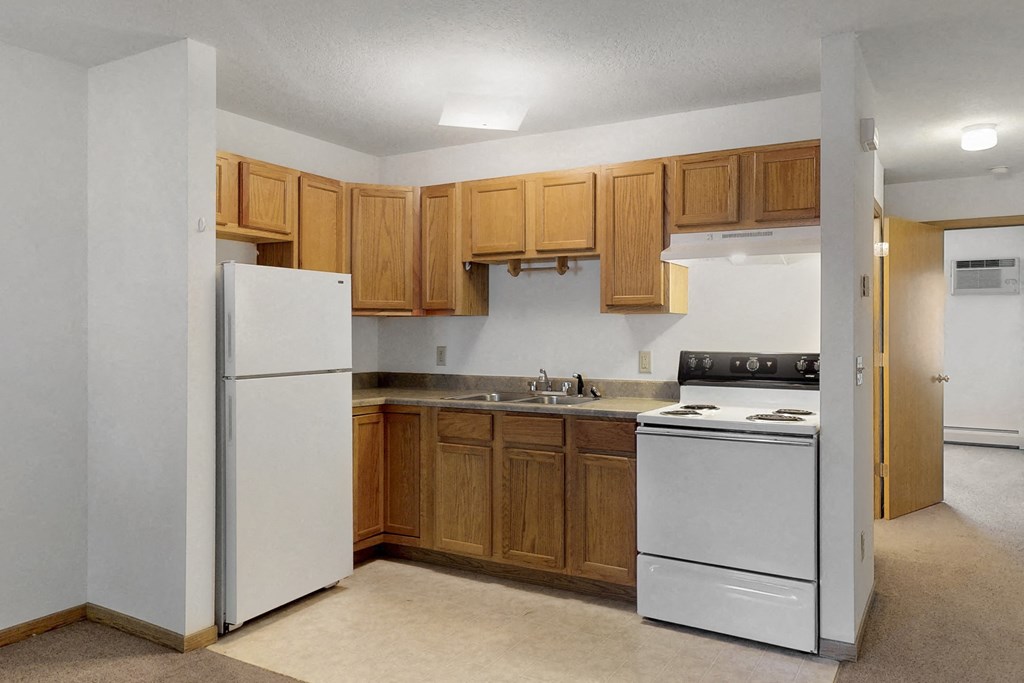 an empty kitchen with white appliances and wooden cabinets