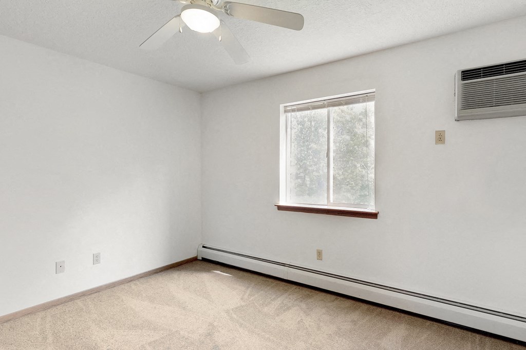 an empty room with a window and a ceiling fan