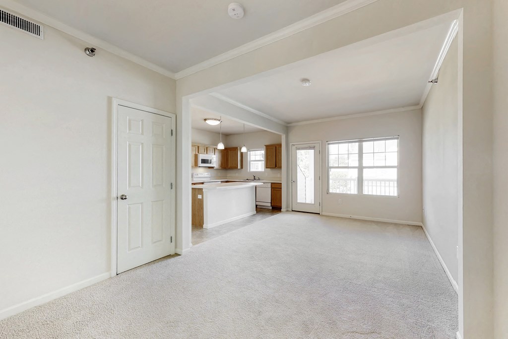 an empty living room and kitchen with a white door