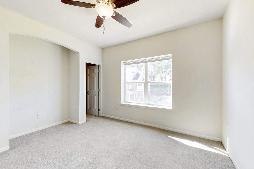 an empty living room with a ceiling fan and a window