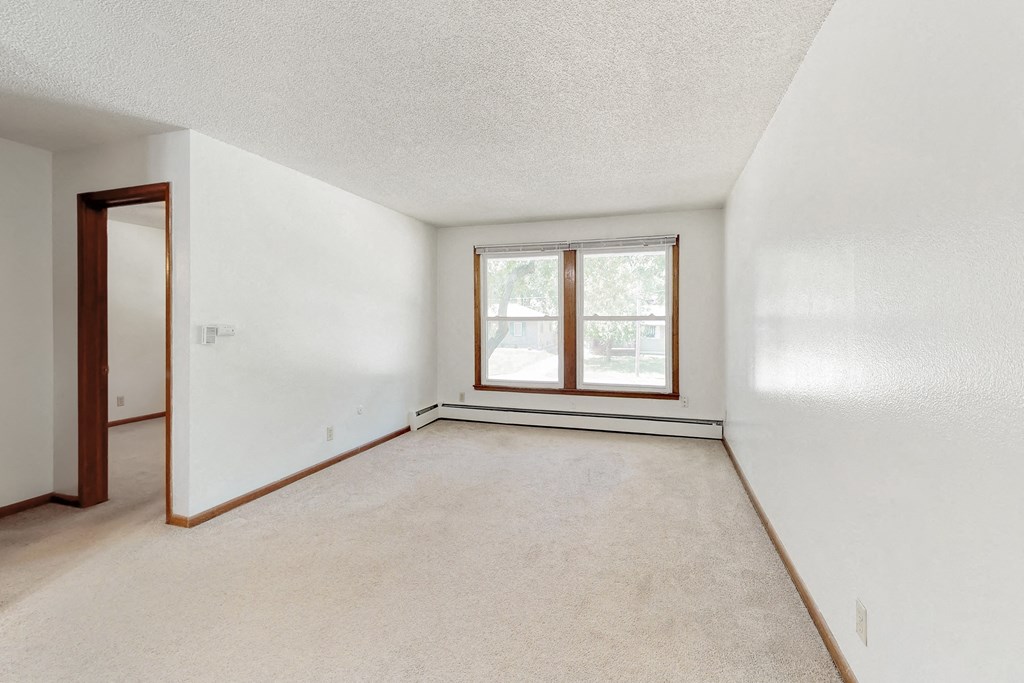 an empty living room with a window and white walls