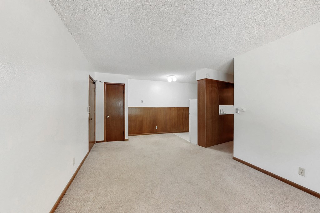 an empty living room and hallway with white walls and wood doors