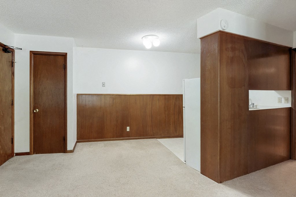an empty living room with wooden doors and a carpeted floor