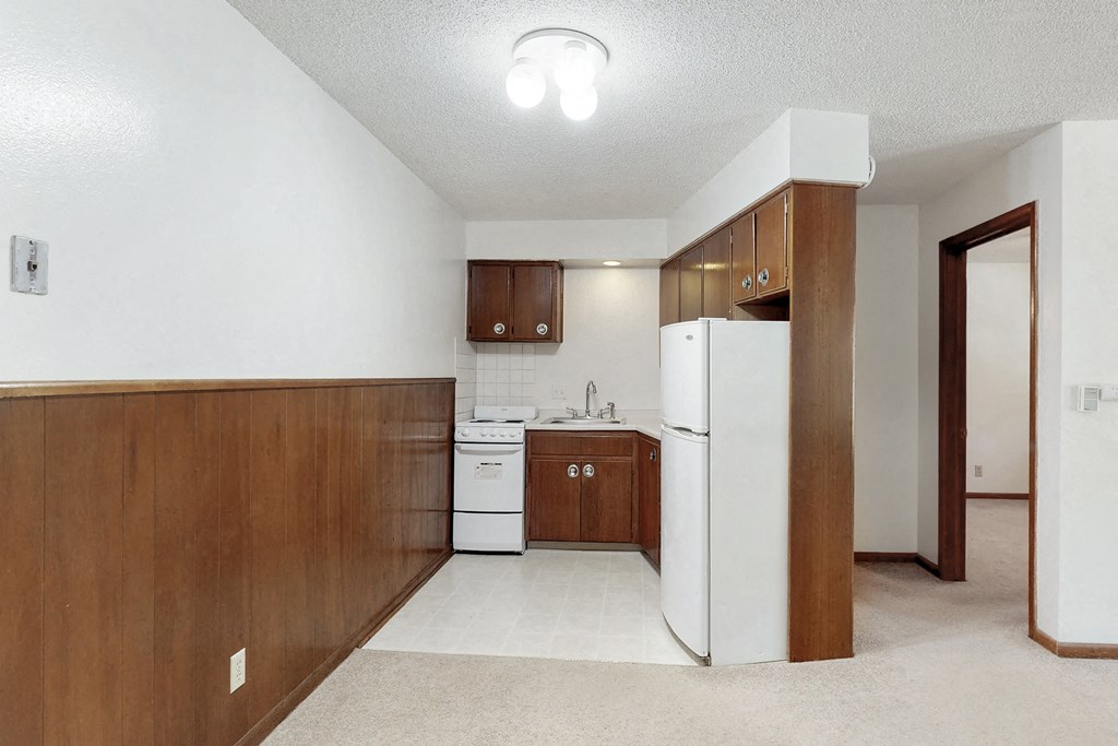 an empty kitchen with white appliances and wooden cabinets