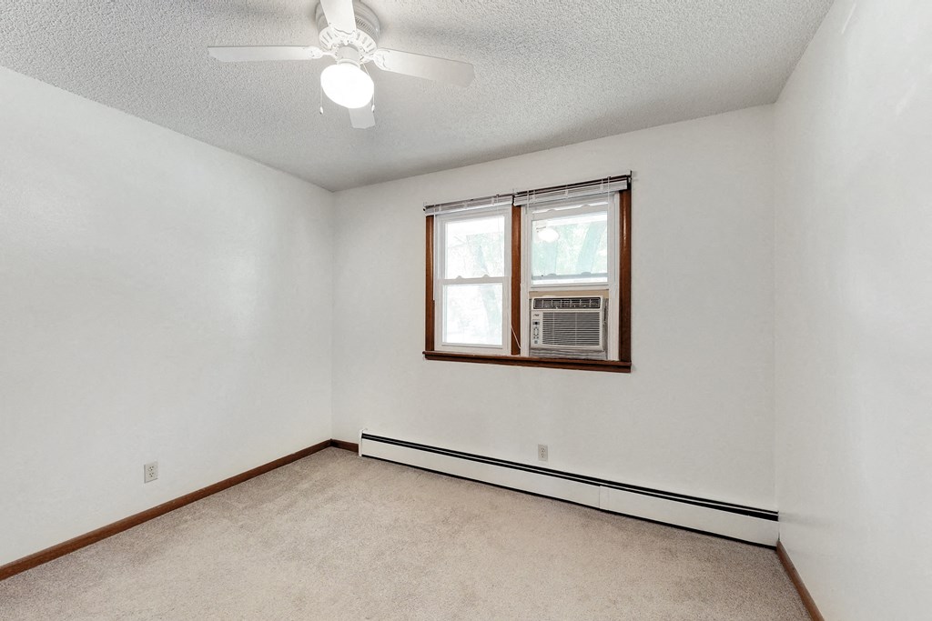 an empty living room with a window and a ceiling fan