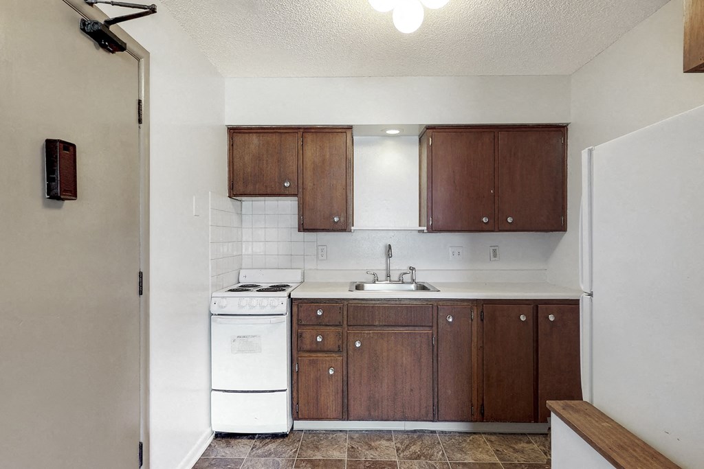 an empty kitchen with white appliances and wooden cabinets