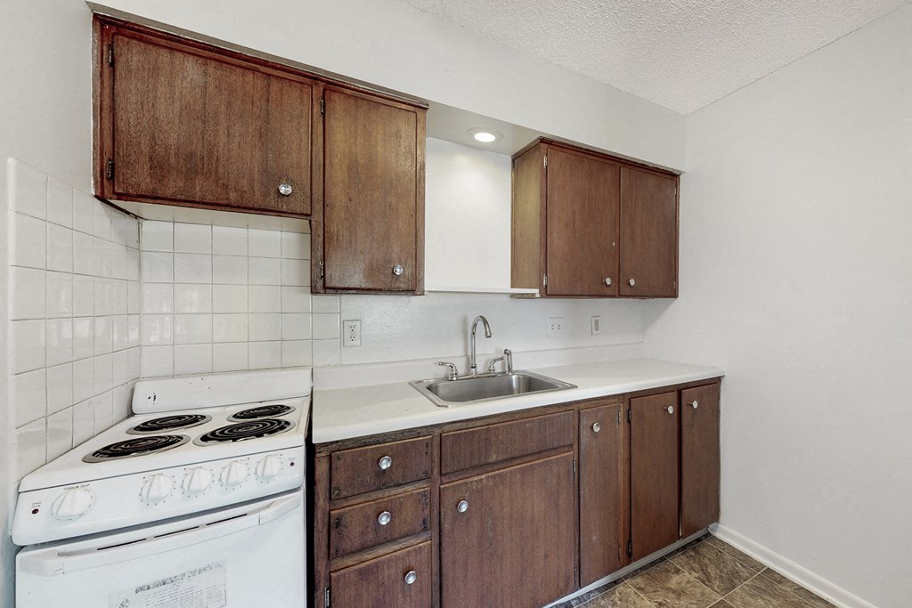 an empty kitchen with white appliances and wooden cabinets