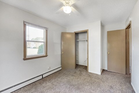 a bedroom with a closet and a window and a ceiling fan