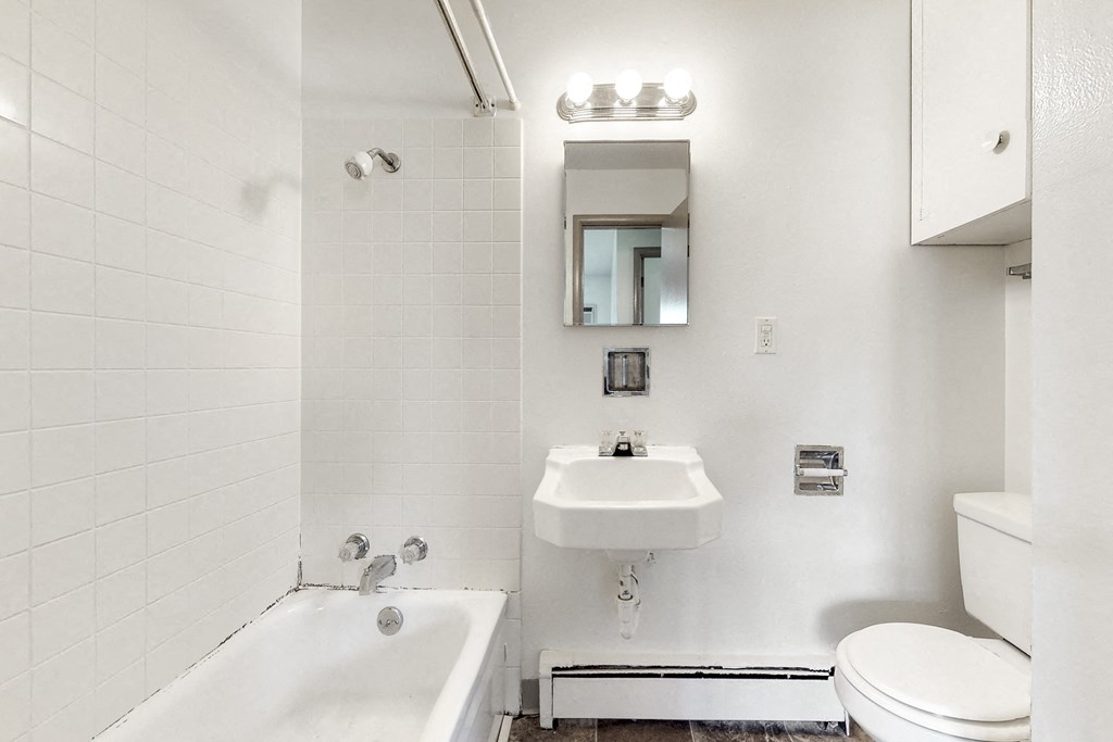 a bathroom with a sink toilet and tub and a mirror
