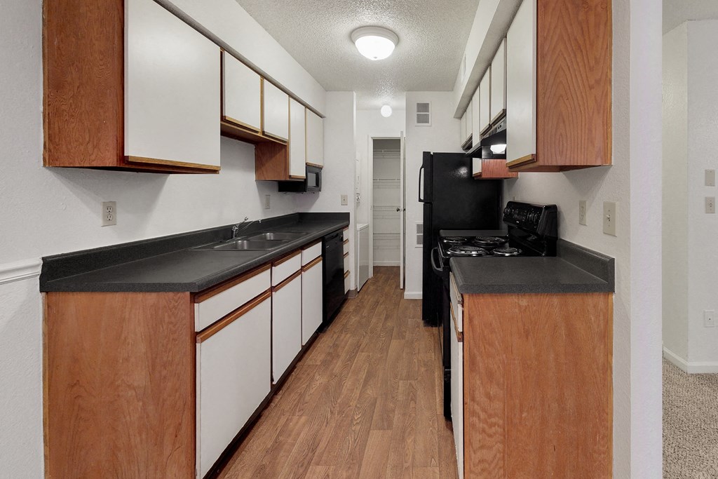a kitchen with black countertops and white cabinets and wood flooring