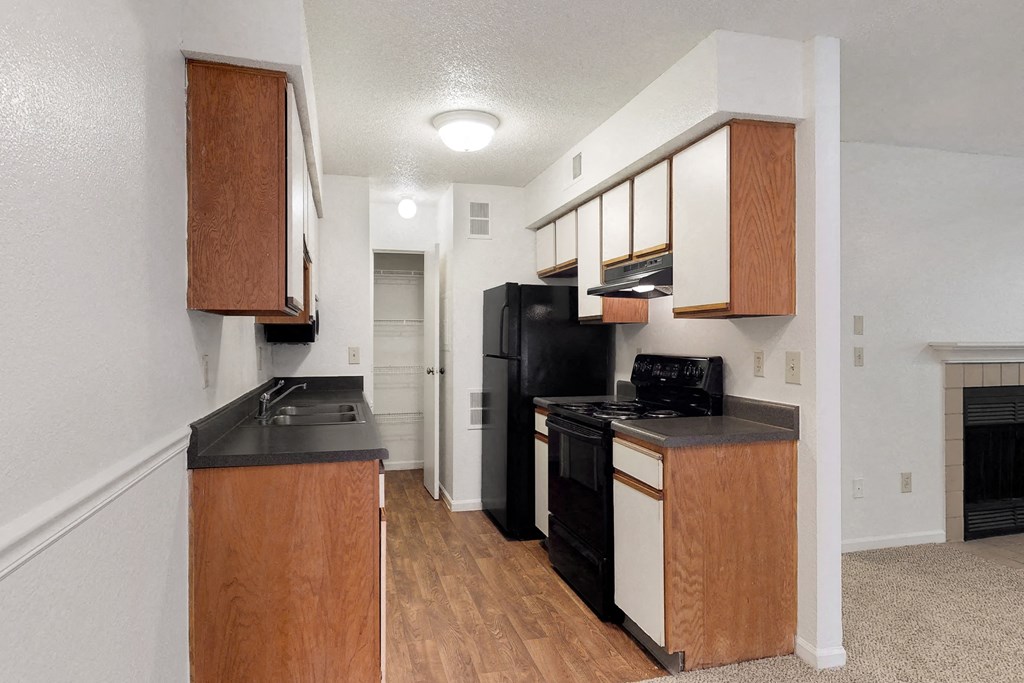an empty kitchen with black appliances and wooden cabinets