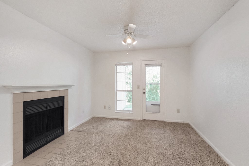 an empty living room with a fireplace and a ceiling fan