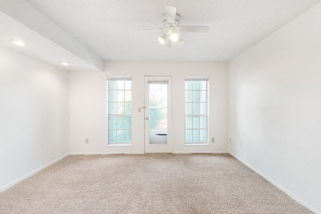 an empty living room with two doors and a ceiling fan