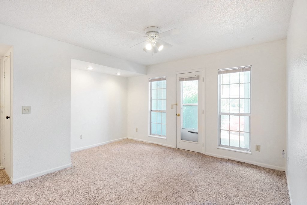 an empty living room with doors and a ceiling fan