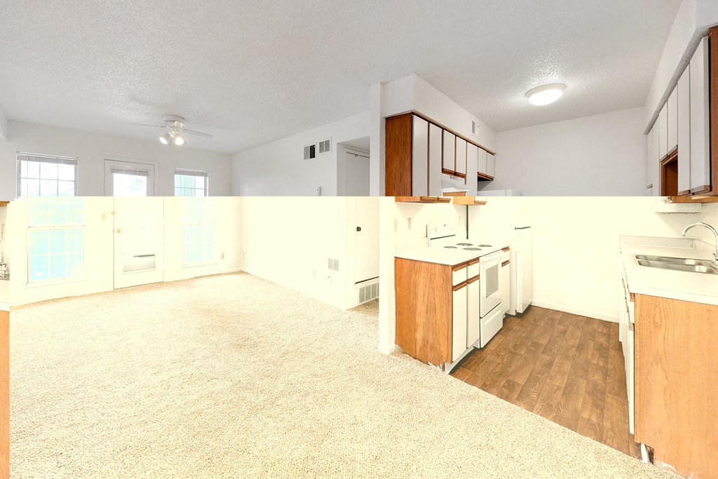 an empty kitchen and living room with wood floors and white cabinets