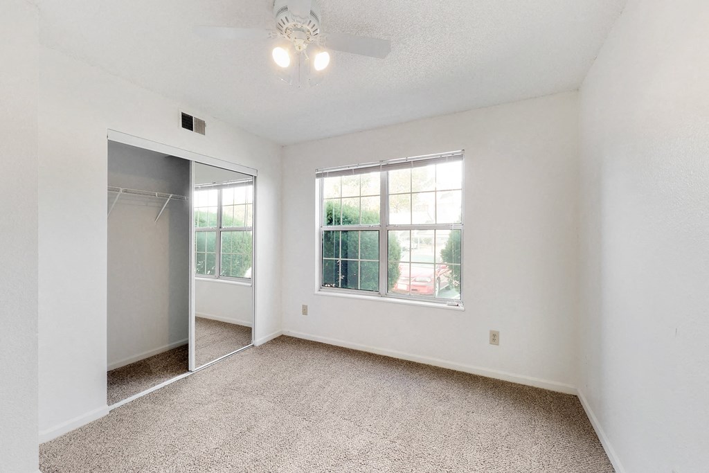 an empty living room with a closet and a large window