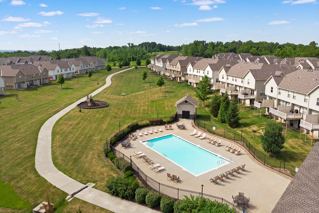 an aerial view of a pool and grassy area with apartment buildings