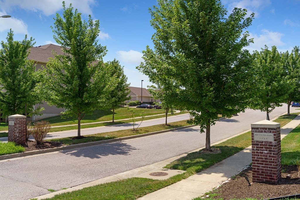 a tree lined street in a suburban neighbourhood with a street sign