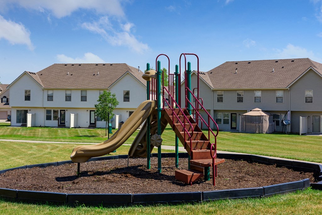 a playground with a slide in front of a house