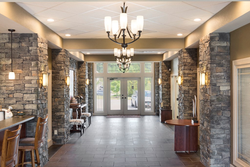 a long hallway with stone walls and chairs and a chandelier