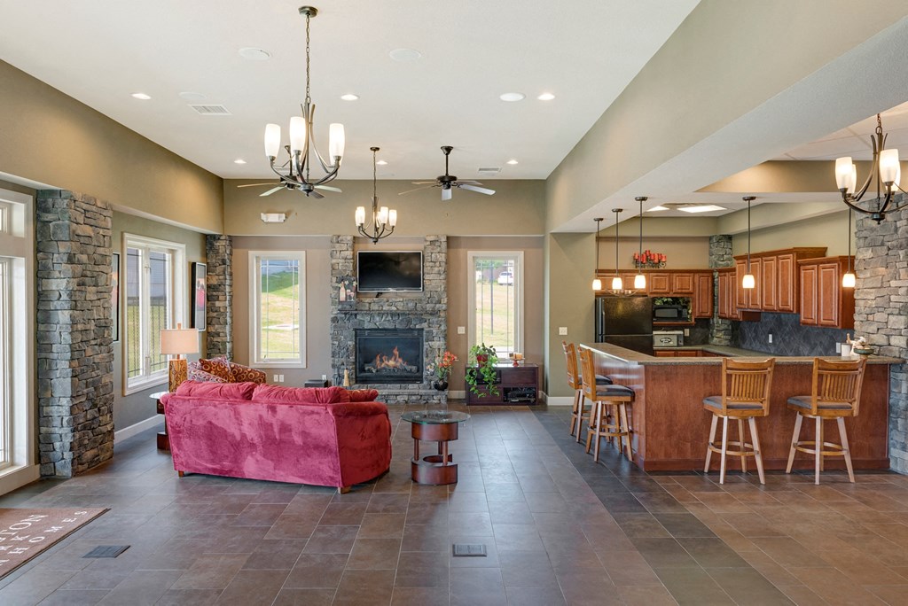 a large living room with a stone fireplace and a kitchen