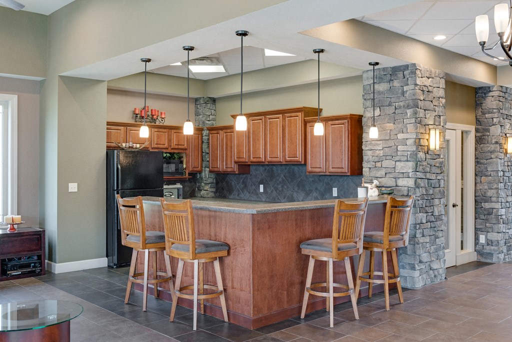 a kitchen with a bar with chairs and a stone wall