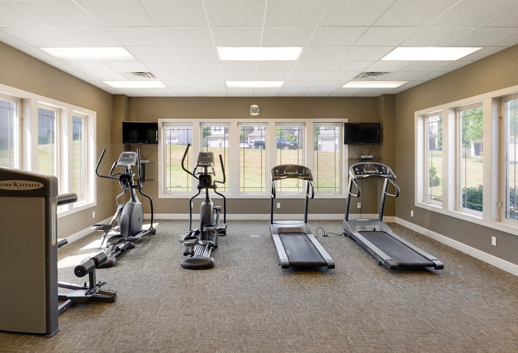 a gym with cardio machines and windows