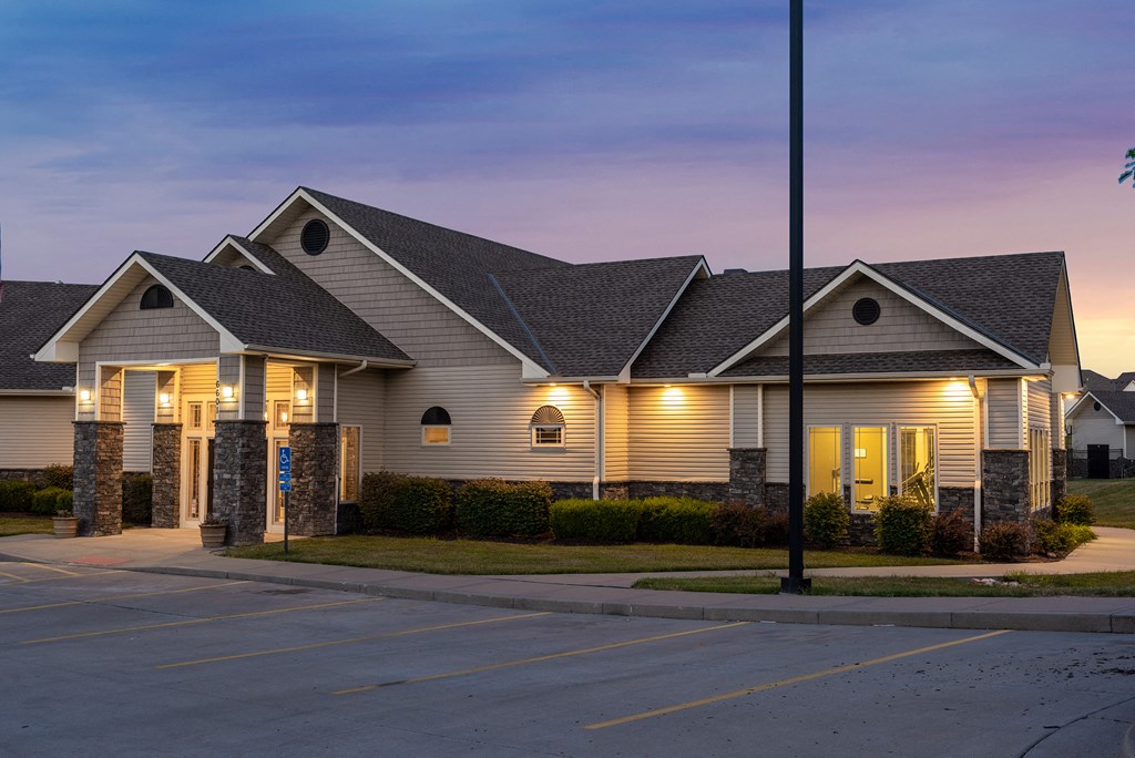 a house with lights on in a parking lot at dusk