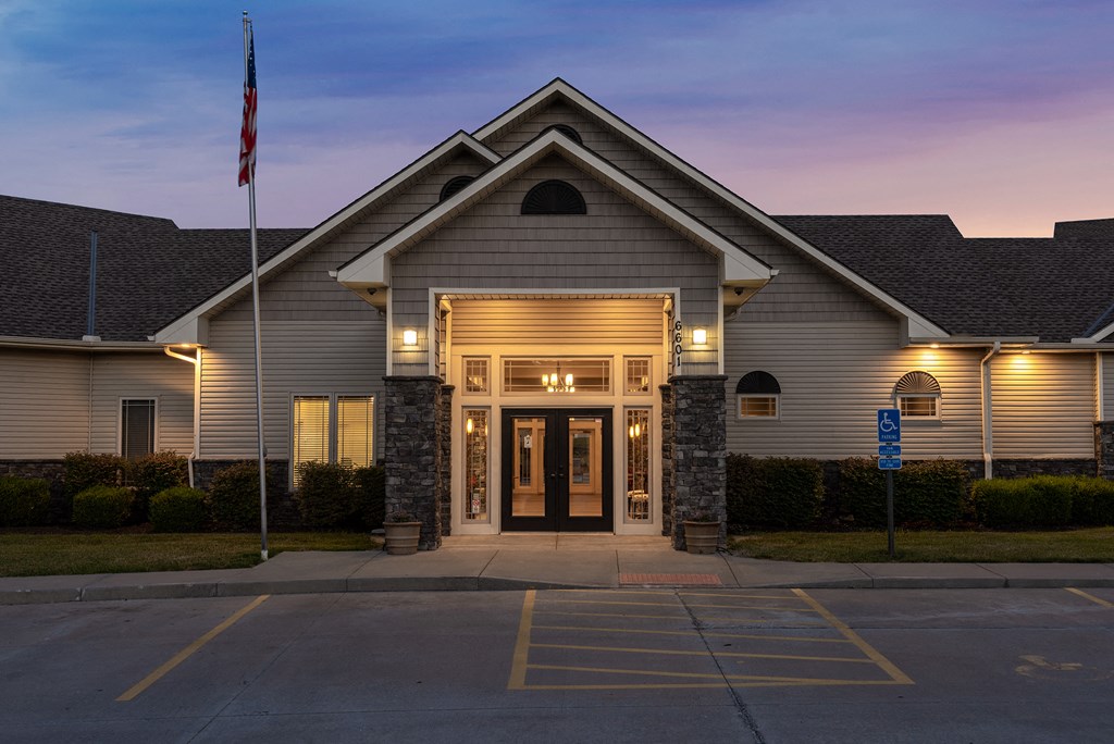 the front of a church building at night with lights on and a flag