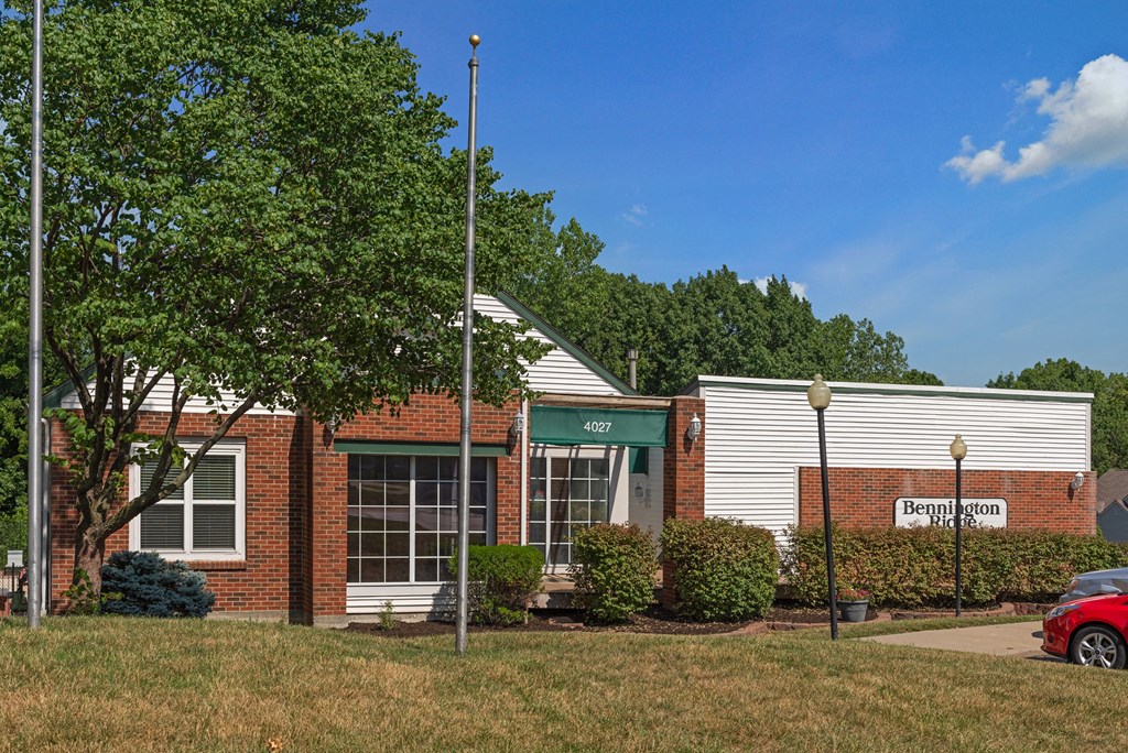 the front of a brick building with a red car parked outside
