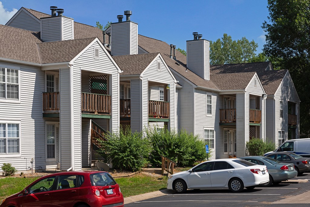 a row of apartment buildings with cars parked in front of them