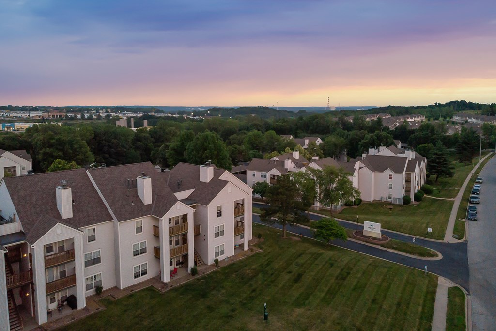 an aerial view of an apartment complex with a sunset in the background
