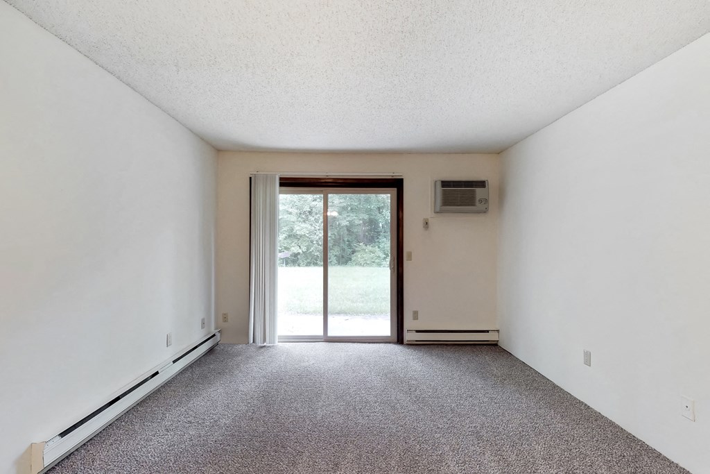 an empty living room with a sliding glass door to a yard