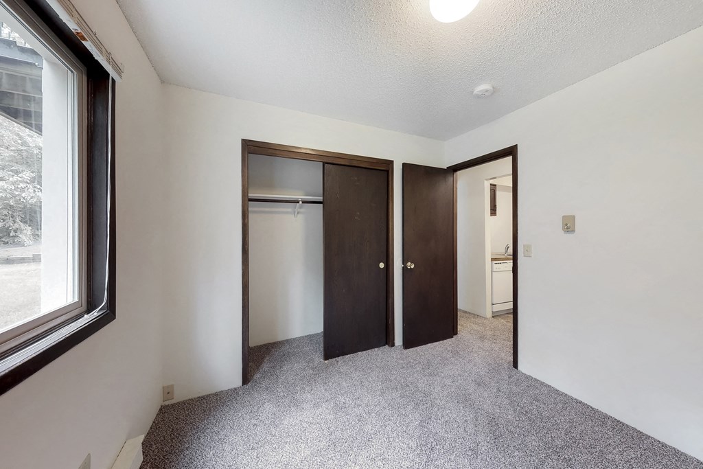 an empty room with a window and two closet doors