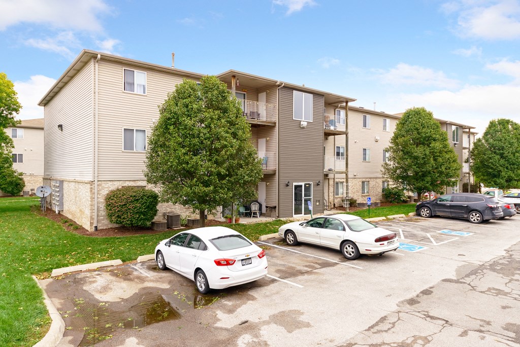 the view of an apartment building with cars parked in a parking lot