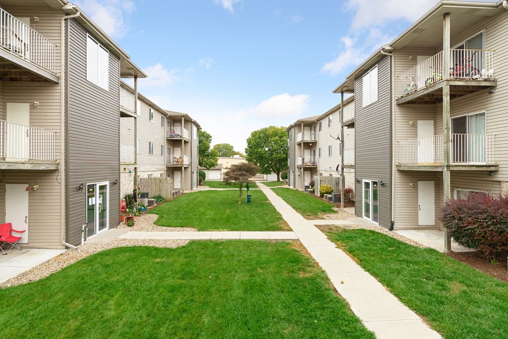 the view of an apartment complex with a lawn and sidewalk