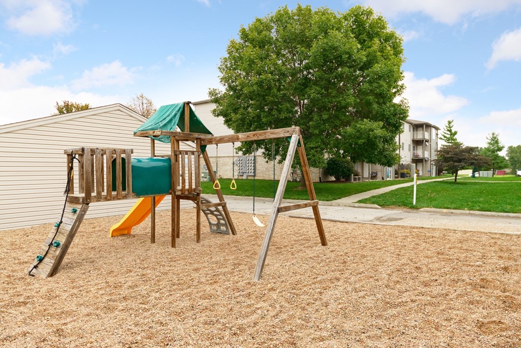 a swing set in a playground next to a house