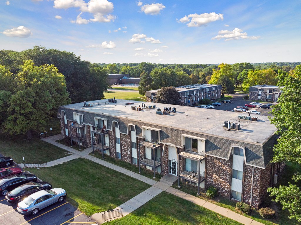 an aerial view of an apartment complex with parking lot and cars